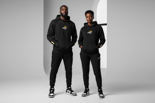 Two people wearing matching black outfits with a logo in a neutral setting